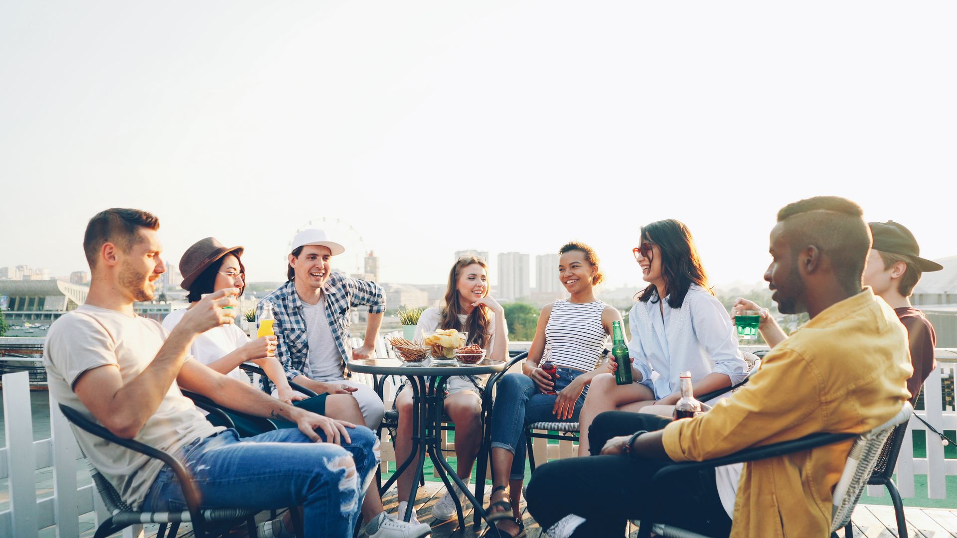 Gruppendate Eine vielfältige Gruppe von Freunden genießt ein Treffen auf der Dachterrasse mit Getränken und Snacks.